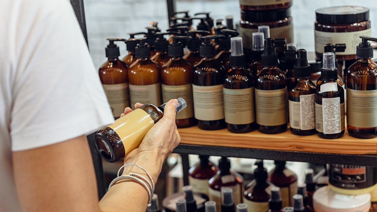A customer choosing an item among organic cosmetic bottled products.