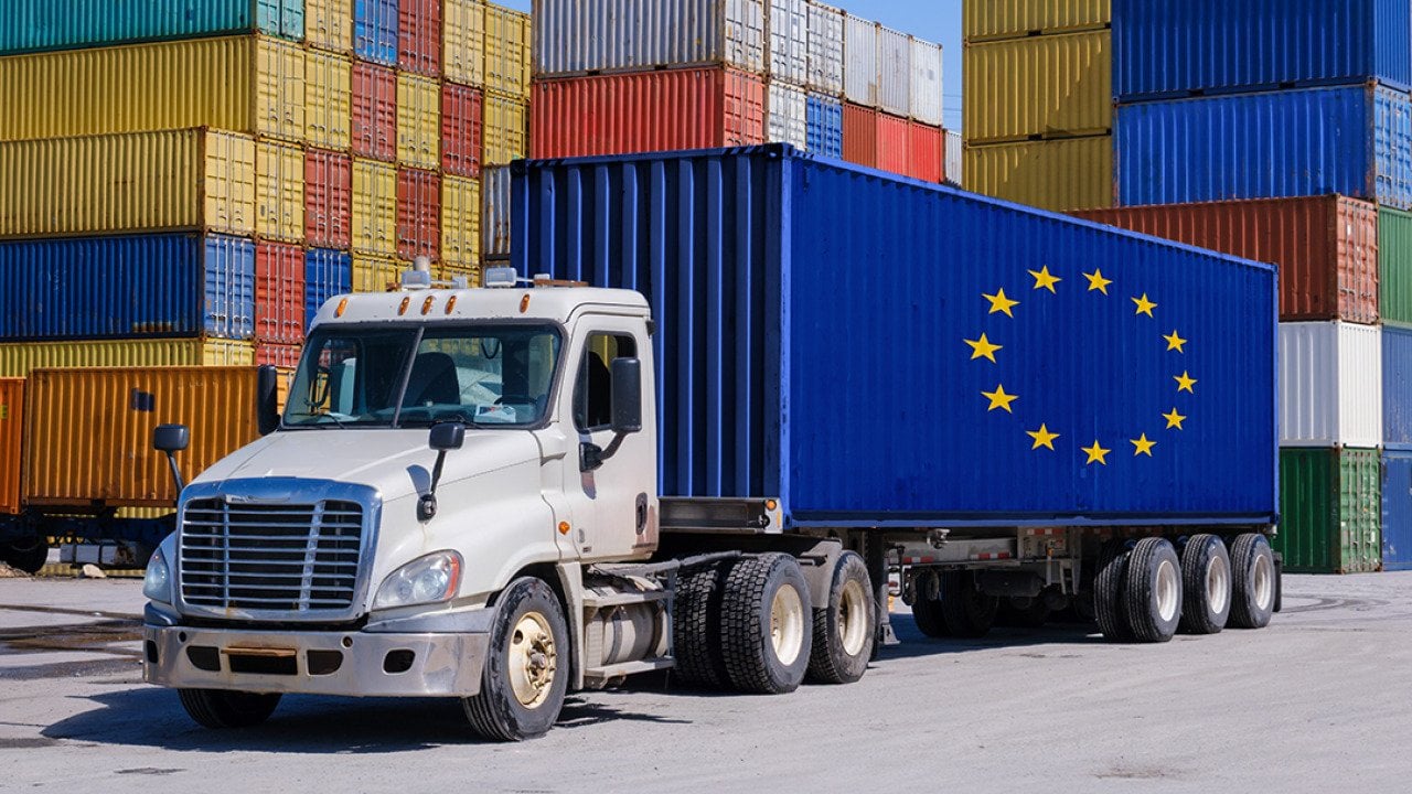 A truck in a shipyard with an EU-marked shipping container.