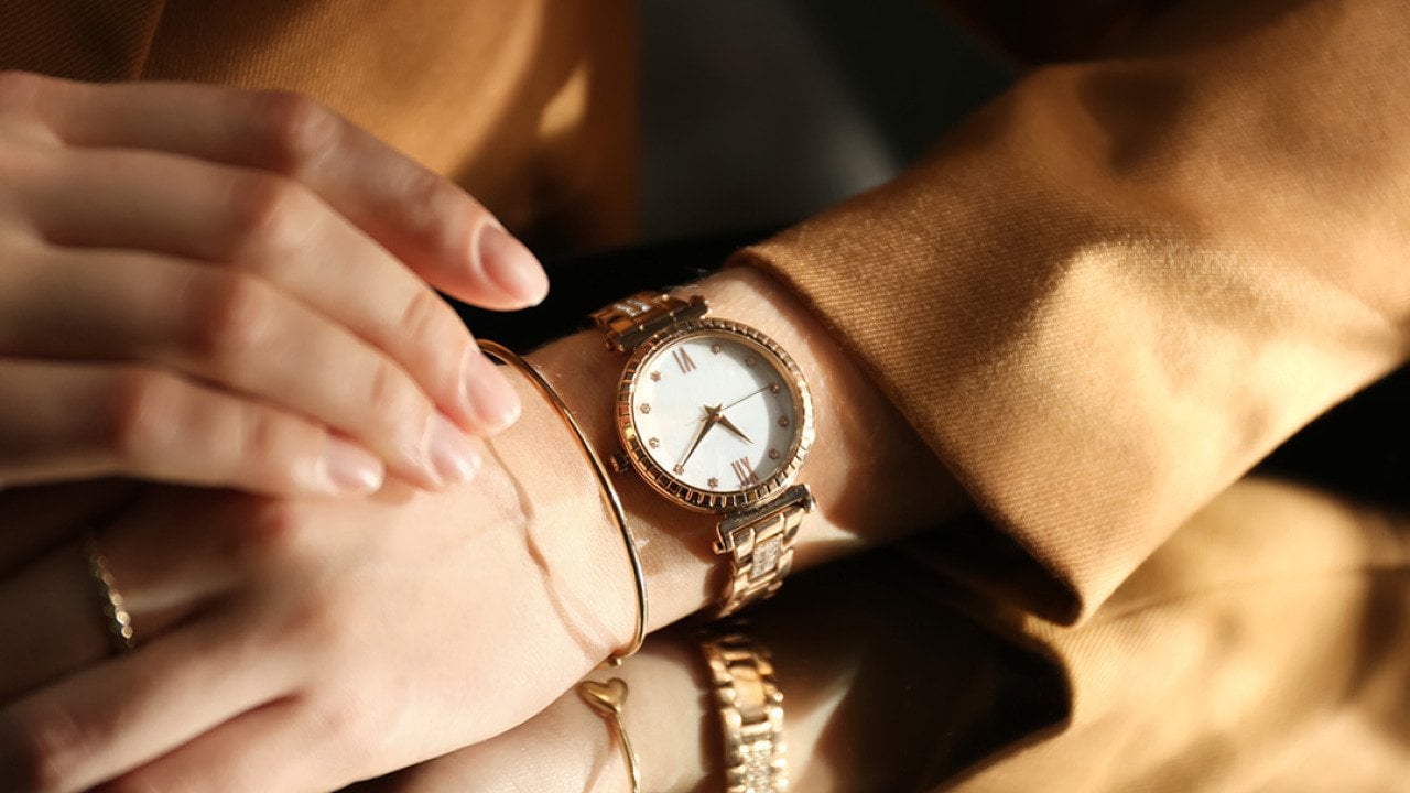 A person wearing a luxury wristwatch over a mirror.