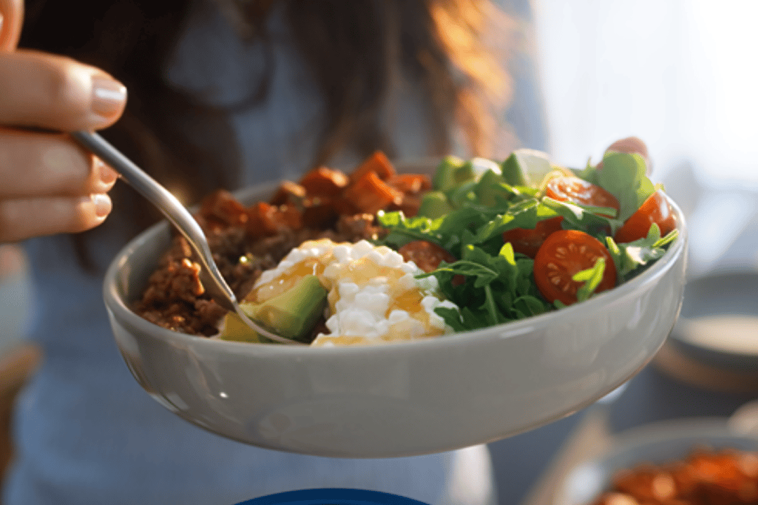 A woman holding a bowl of salad with cottage cheese.