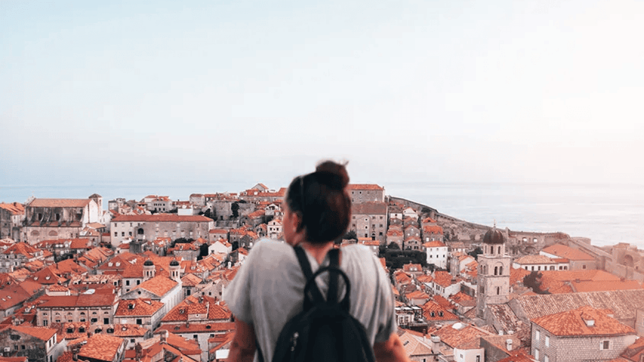 A young tourist looking over red-brownish roofs from Old Town in Dubrovnik, Croatia.
