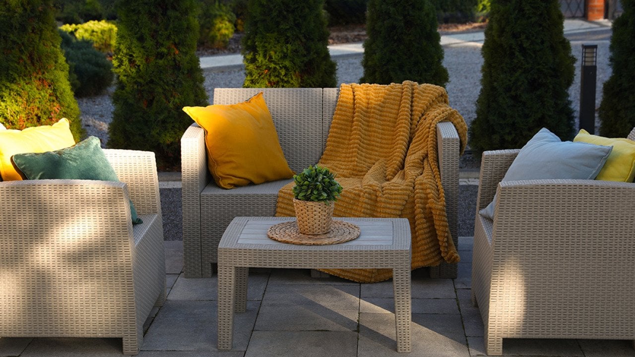 An outdoor rattan garden furniture set with yellow and cream motifs.