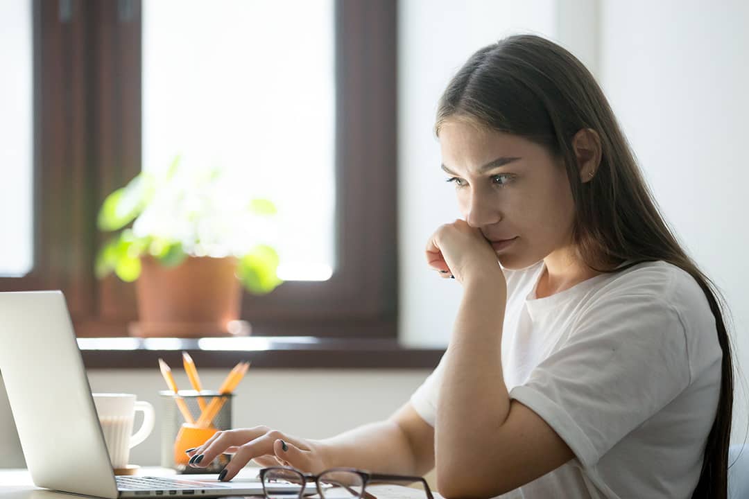 A person appearing to be suspicious while reading from a misleading online content from a laptop.