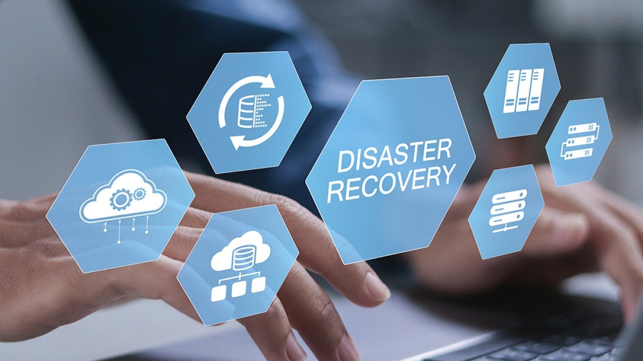 Businessman typing over a keyboard illustrated with conceptual graphics for a cyber disaster recovery system.