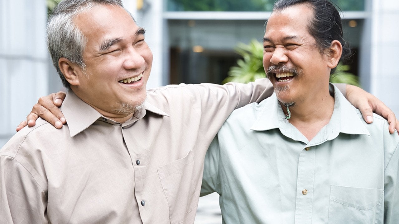 Two older male friends happy to see each other during a reunion.