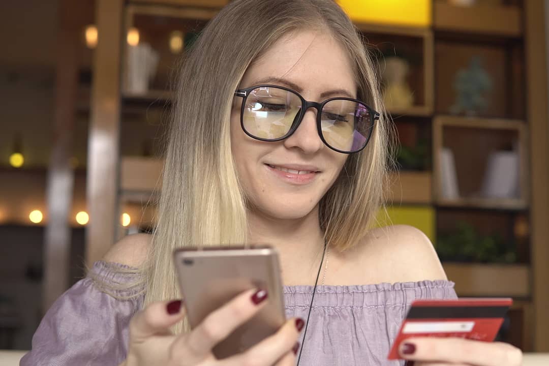 A woman shopping online using her phone and credit card.