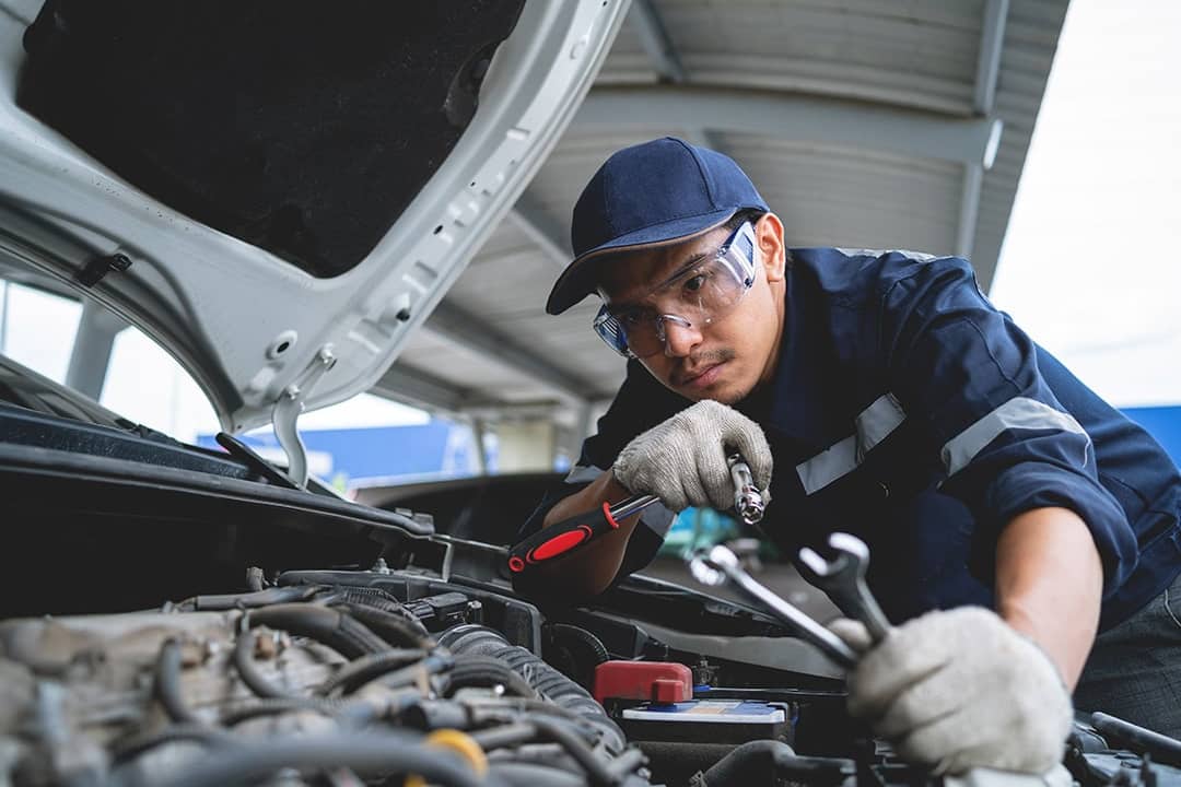 A mechanic working on a repair and service for a car engine in a garage.