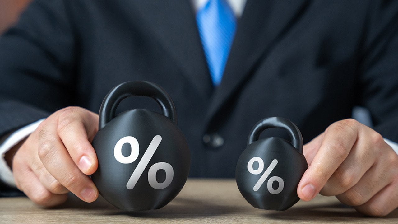 Businessman holding two weights side by side as a concept of concept of debt burden.