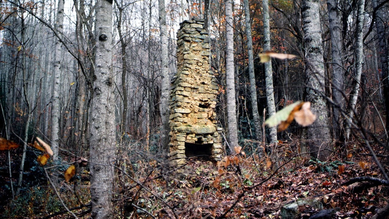 A stone chimney is seen from a 19th century log cabin located in the Appalachian Mountains in Northern America.