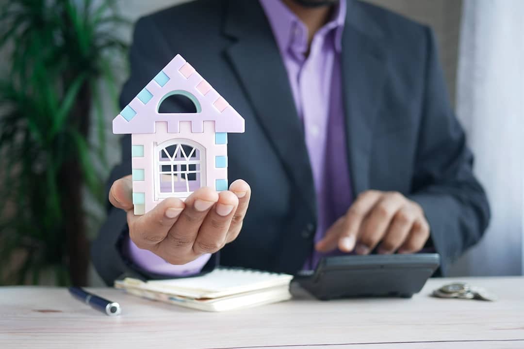 A finance professional holding a small figure of a house as a concept of investing in real estate.
