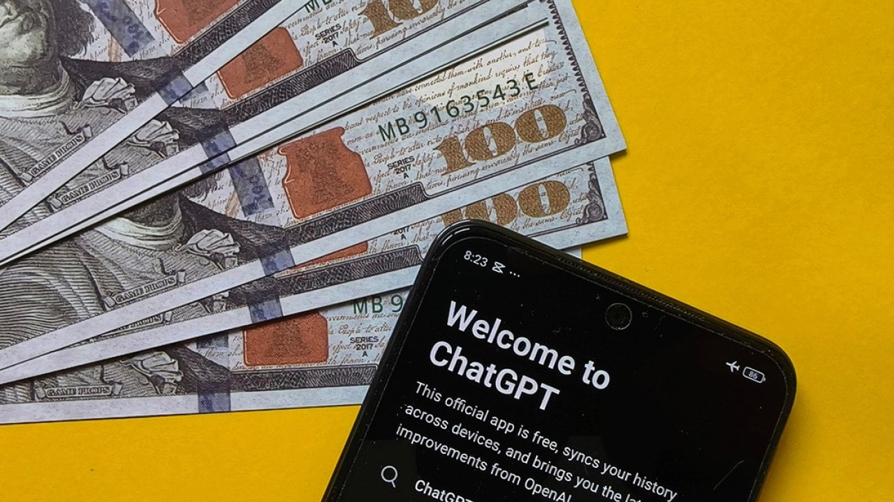 US 100 dollar banknotes and a smartphone displaying ChatGPT in a yellow background, symbolizing the concept of financial AI.