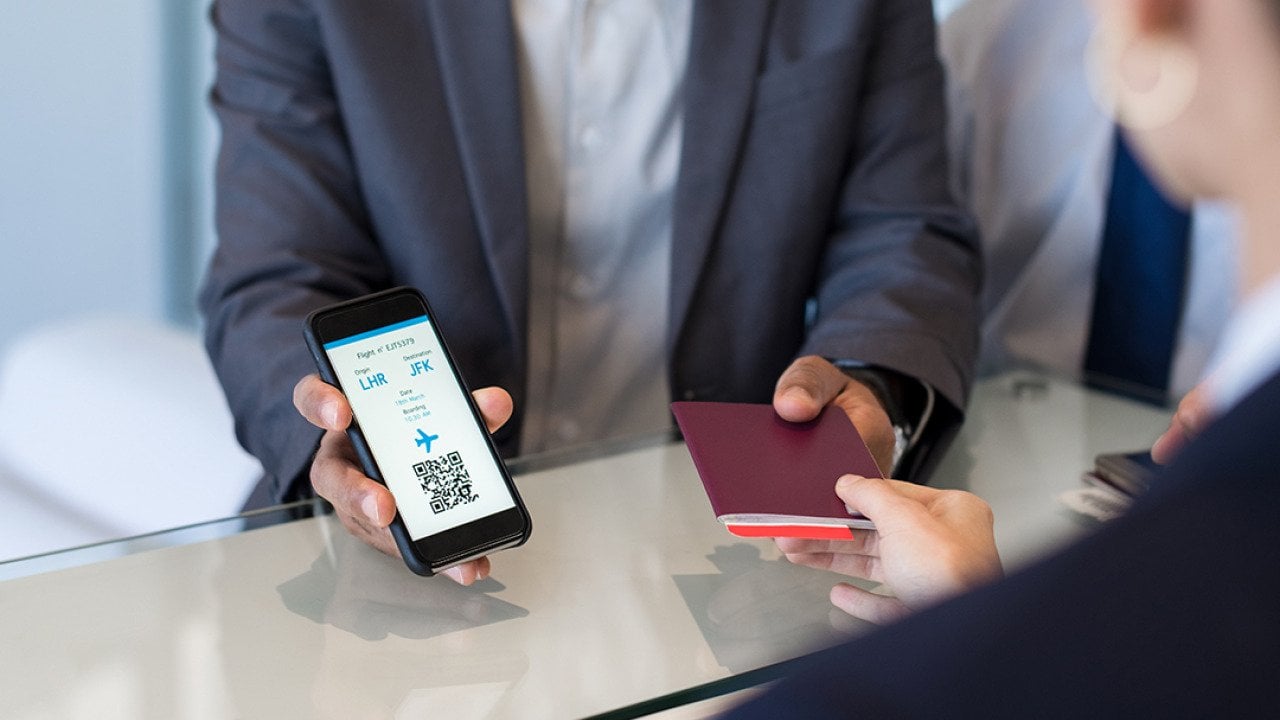 A businessman showing passport and flight ticket using his smartphone at airport check-in.