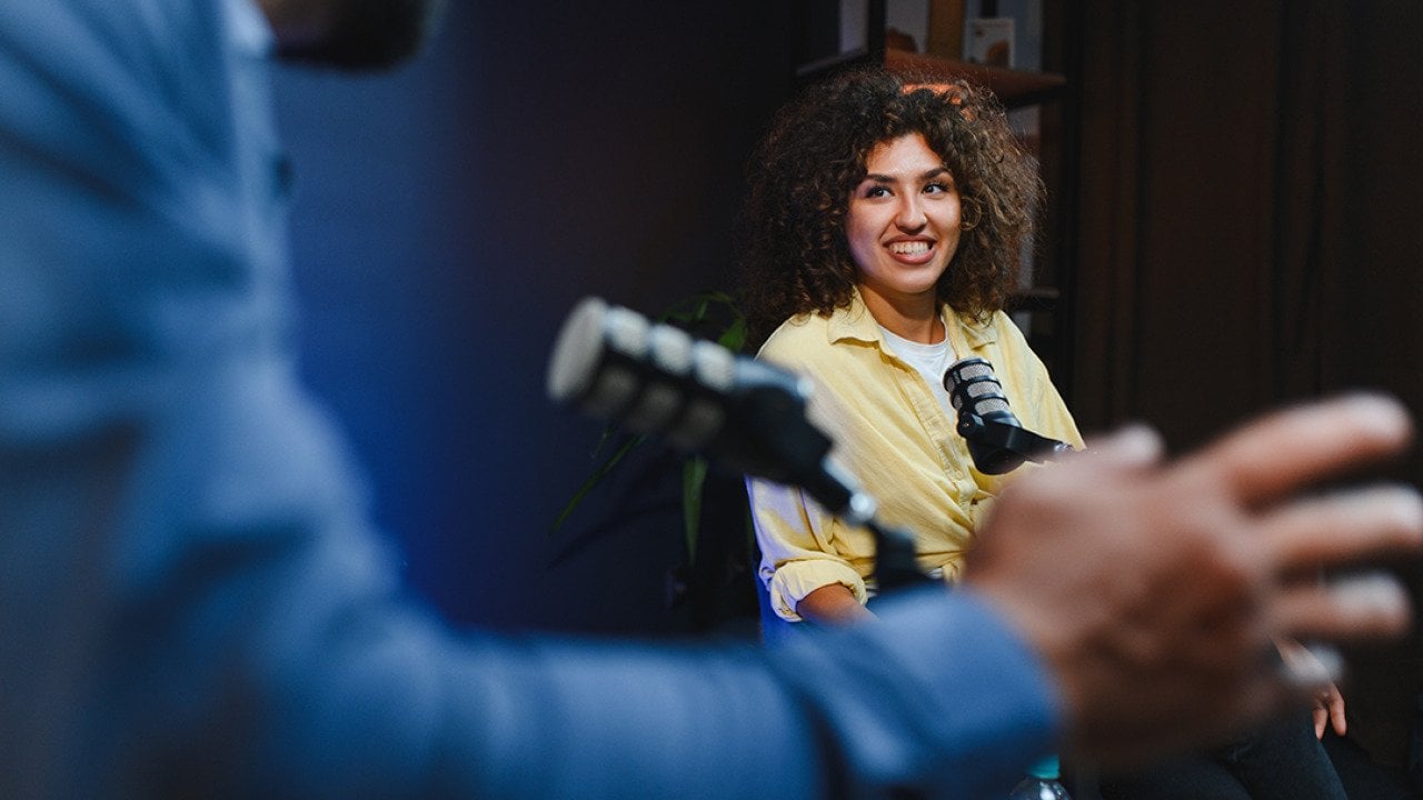 Two podcast hosts happily engaging in discussion for their recording session.