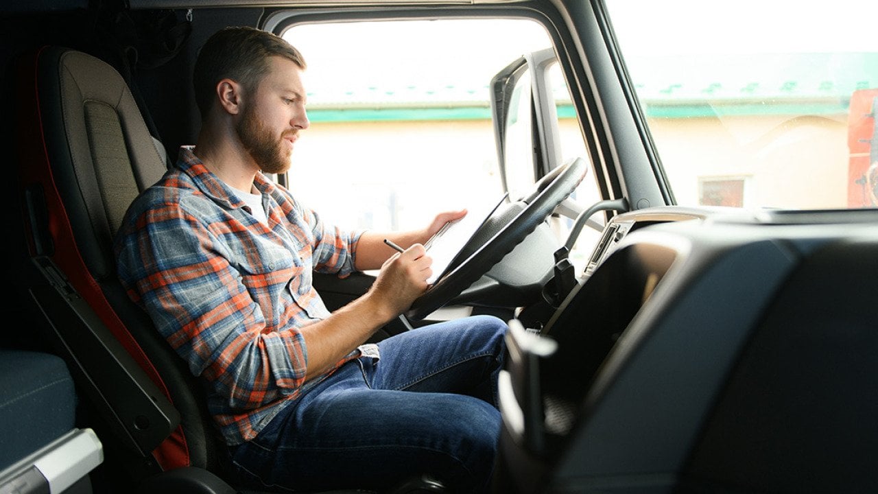 A driver checking cargo documents inside a truck before transportation.