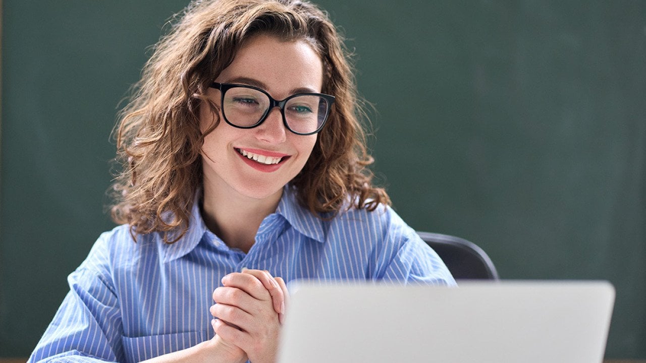 A teacher looking excited while reading good news online.