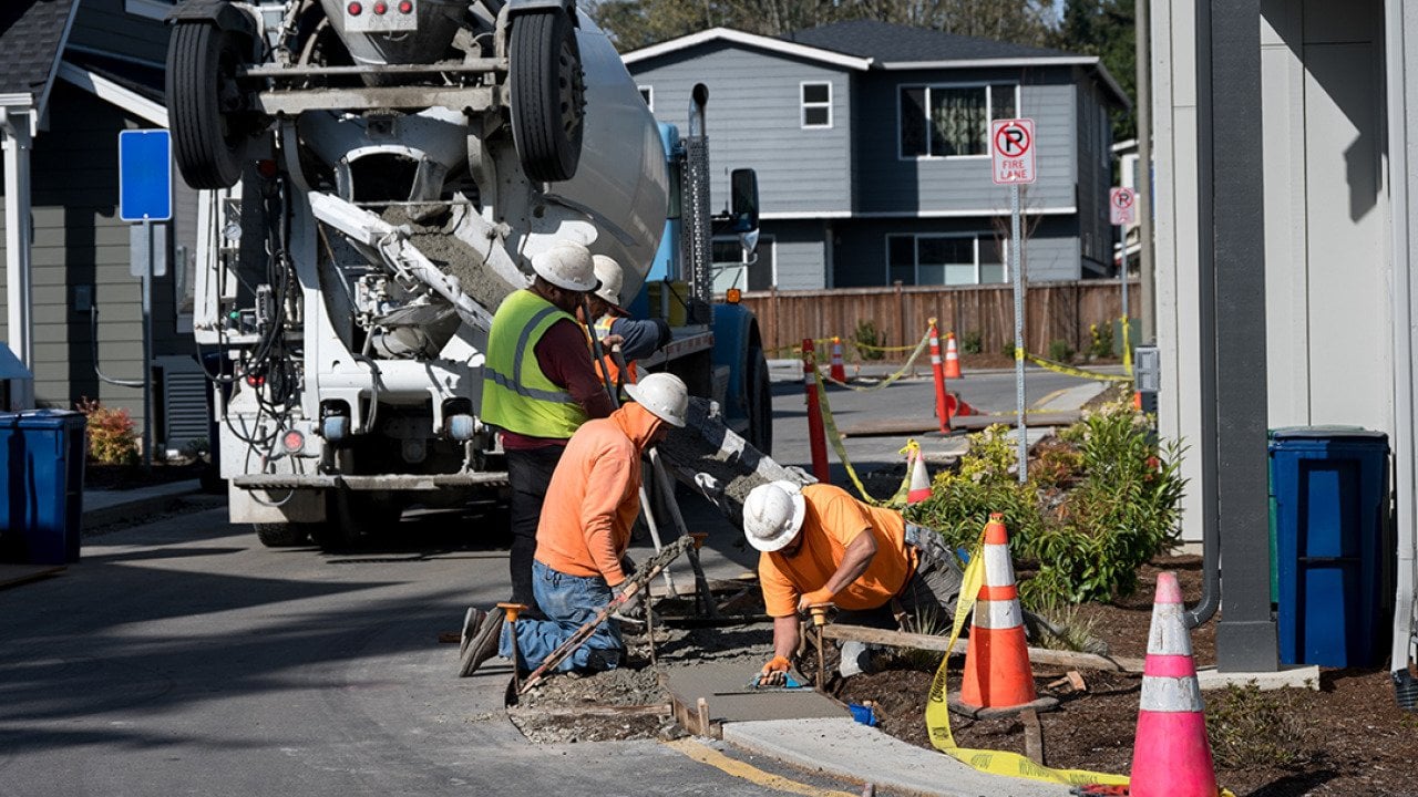  A group of construction workers smoothening a wide concrete curb.