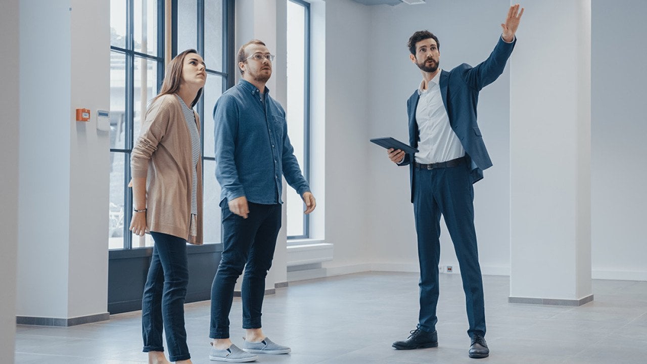 A real estate agent showing an empty office space for rent to clients.