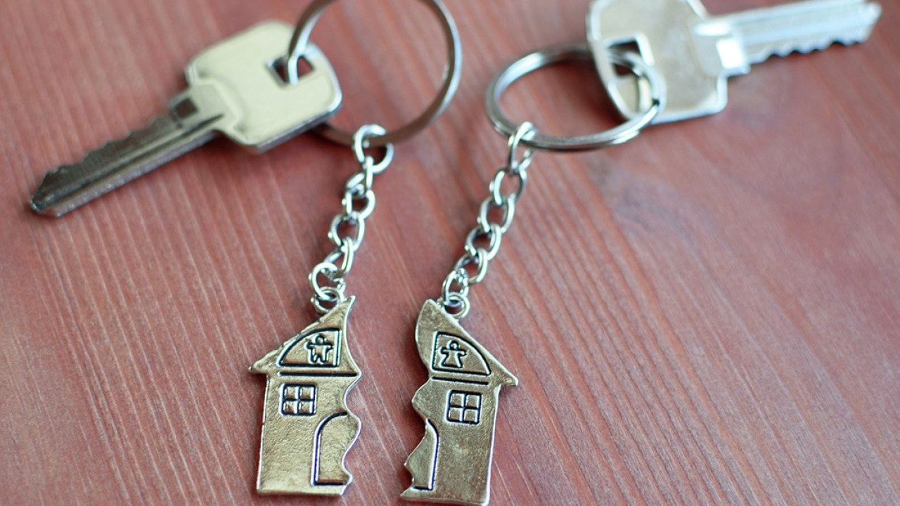 Two keys with split house pendants laid in a wooden background.