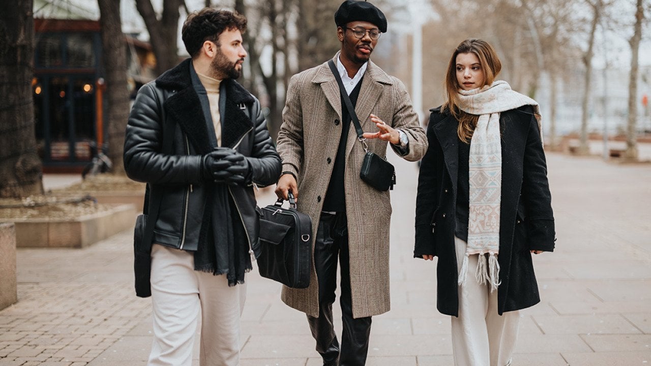 A group of stylish young entrepreneurs walking together outdoors engaged in a conversation.
