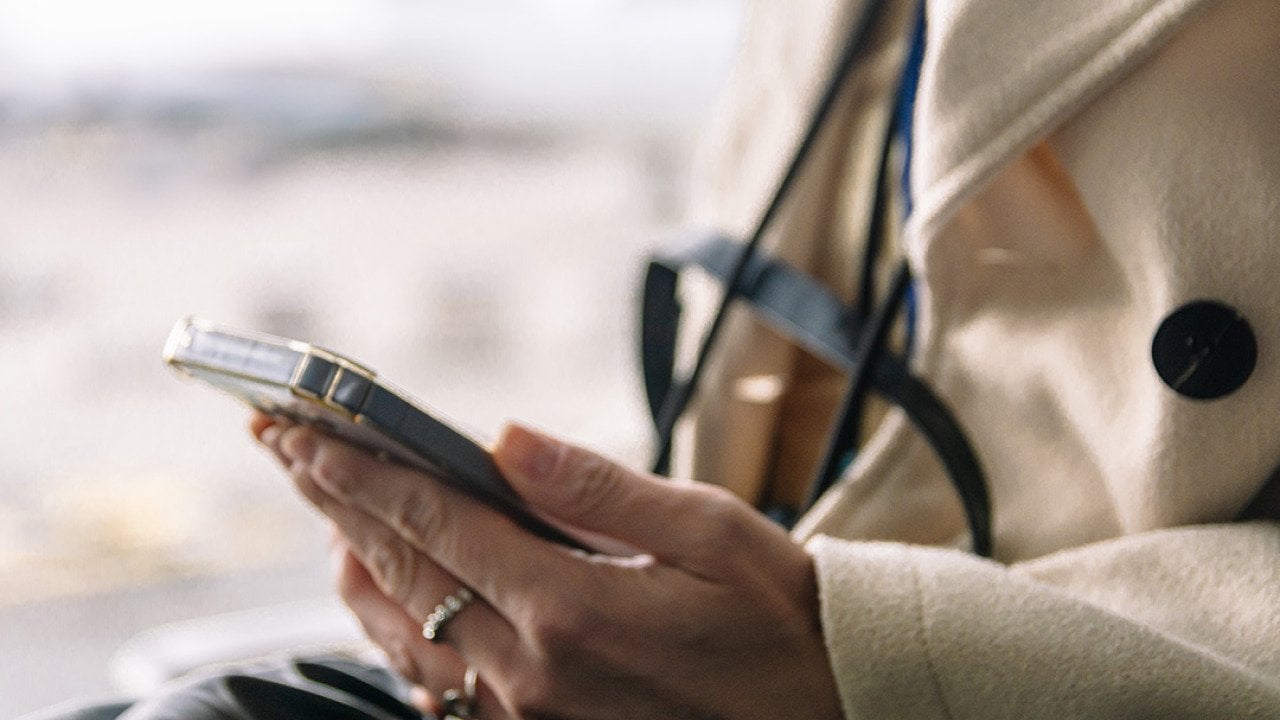 A person checking flight details from her smartphone in the airport.
