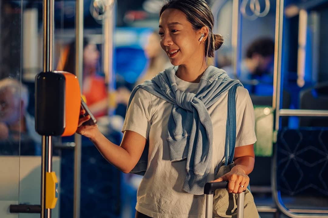 A female tourist paying for bus fare using smartphone NFC technology