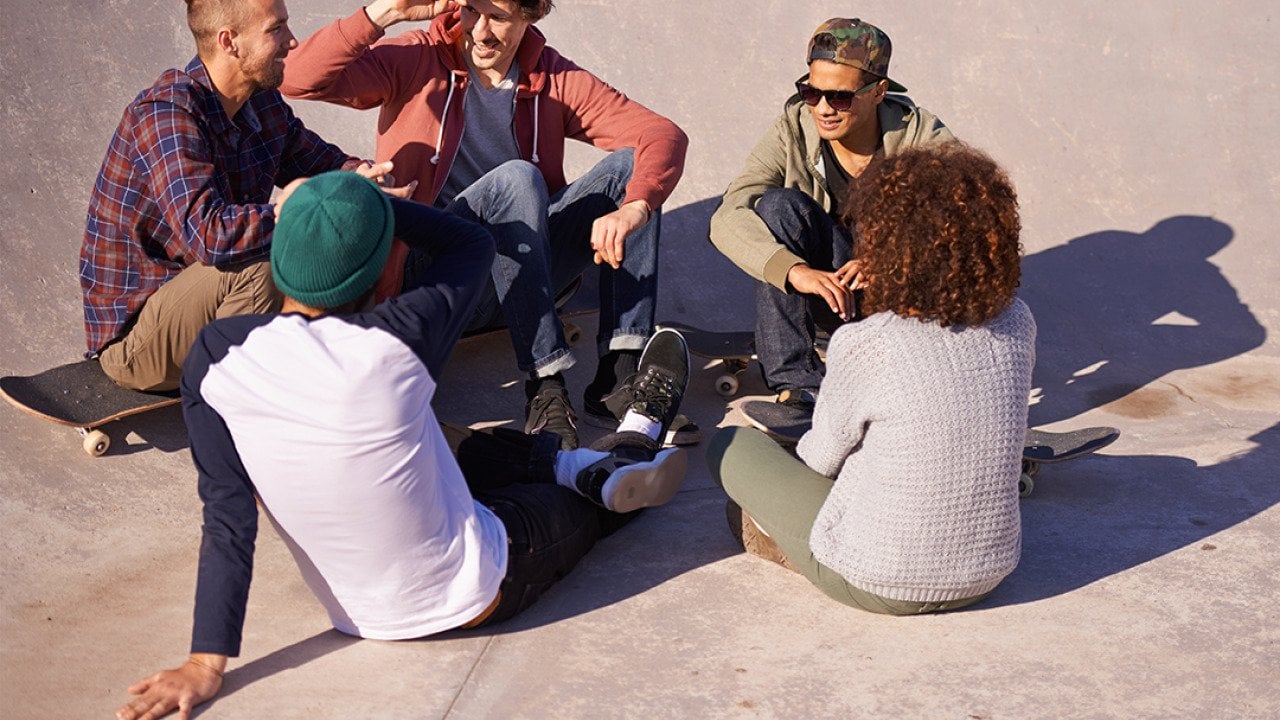 A group of adult skaters hanging out under the sun in a skate park.