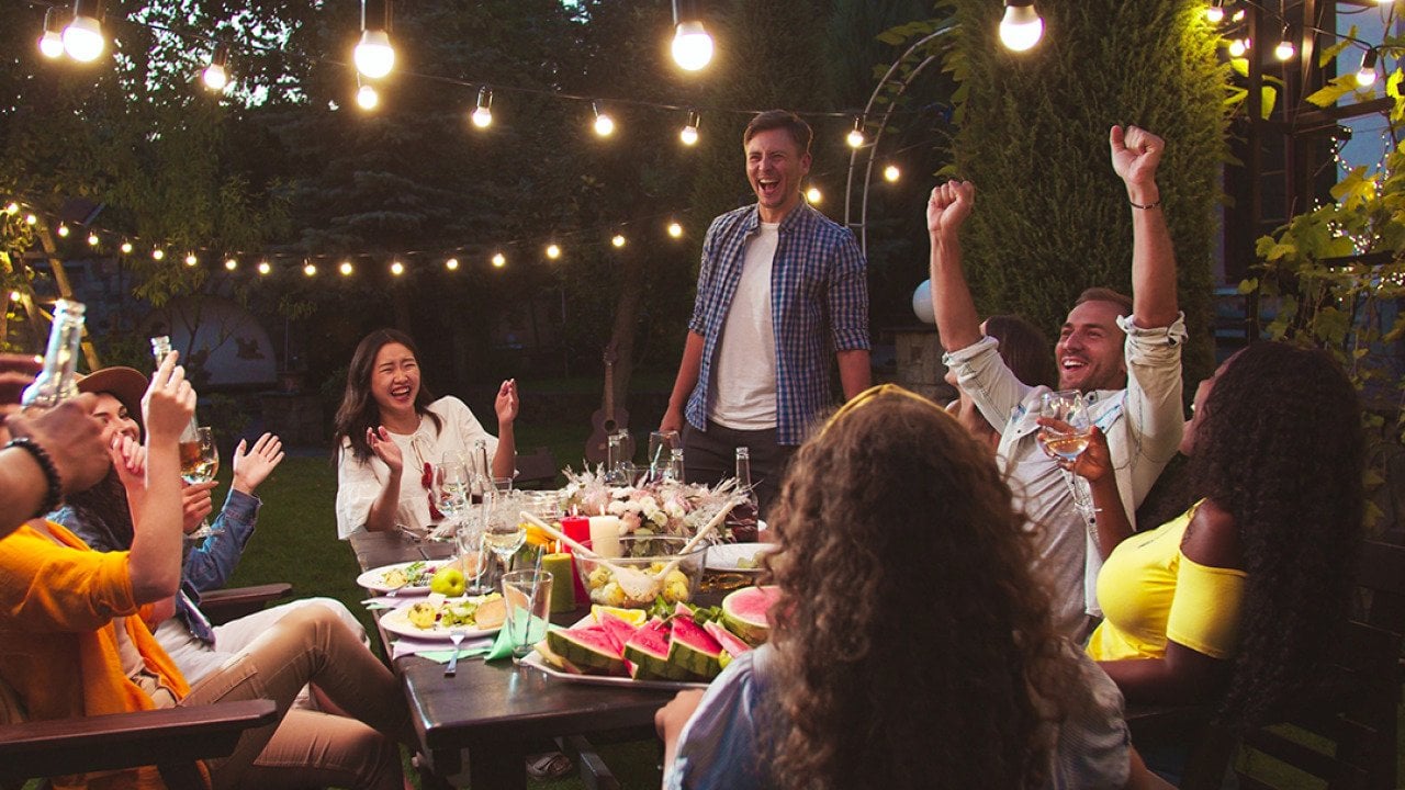 A diverse group of friends having a party at a backyard at night.