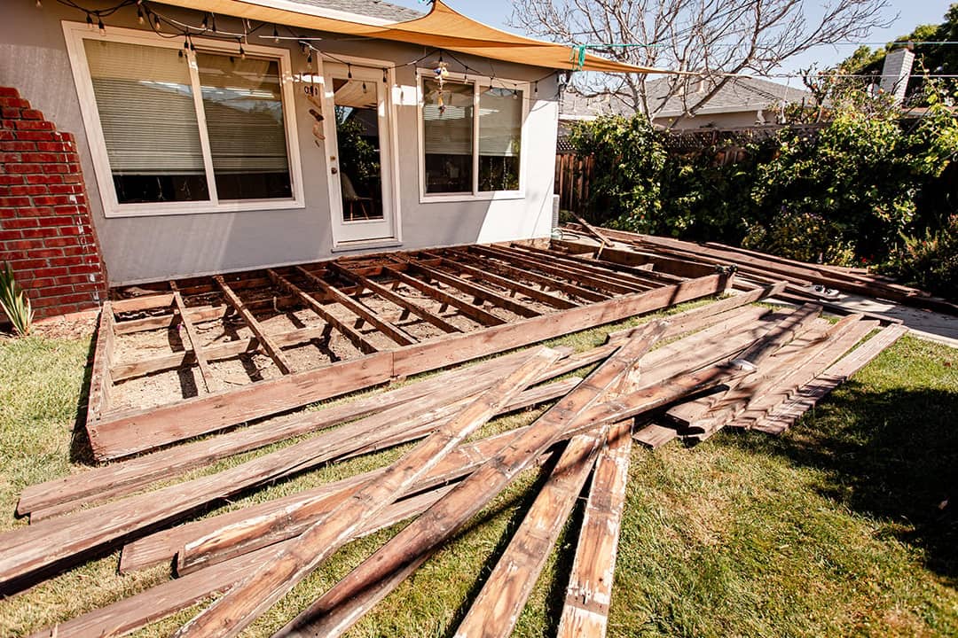 A pile of broken and old wooden lumber laying on the lawn backyard.