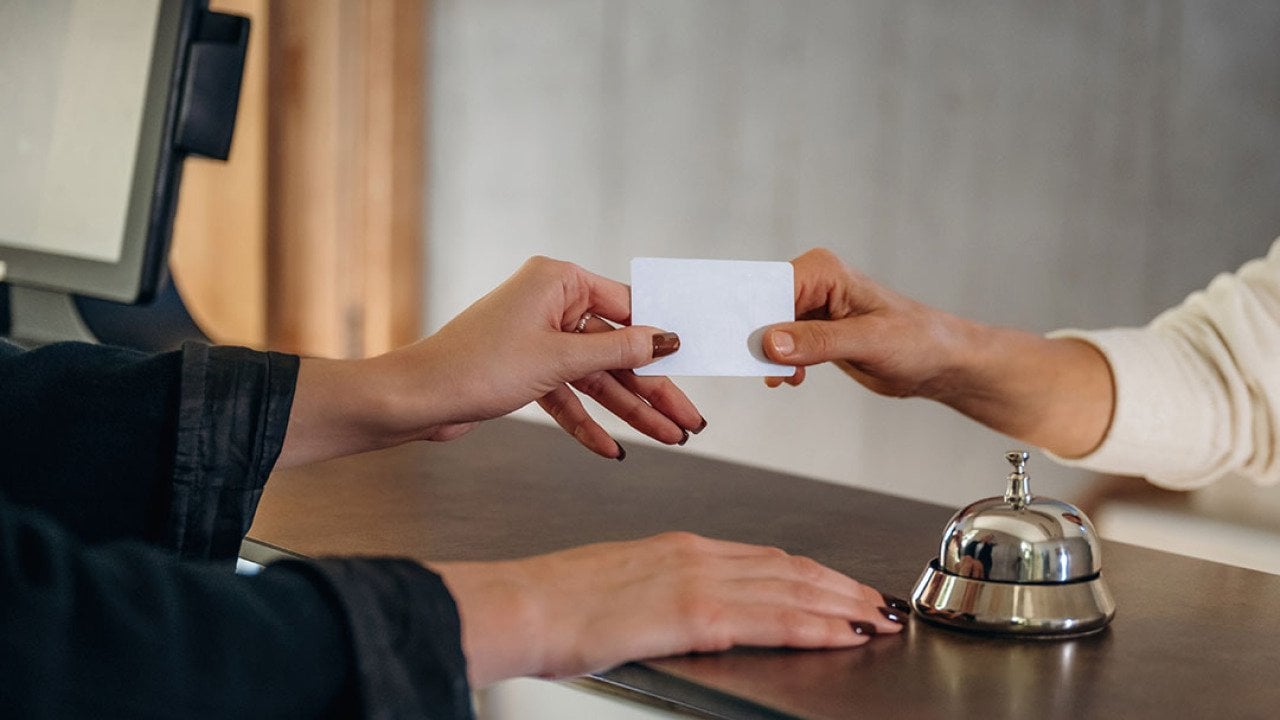 A professional handing credit card over to hotel receptionist to check in.
