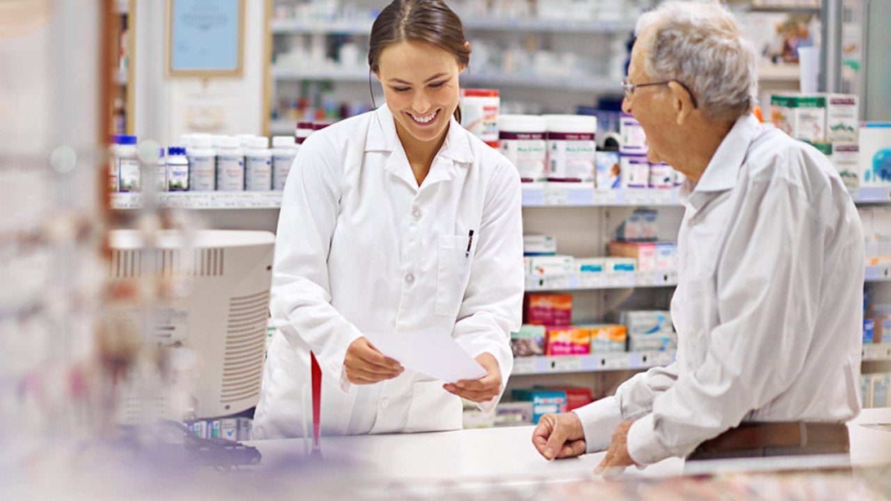 A pharmacist helping an elderly customer for prescription medicines at the counter.