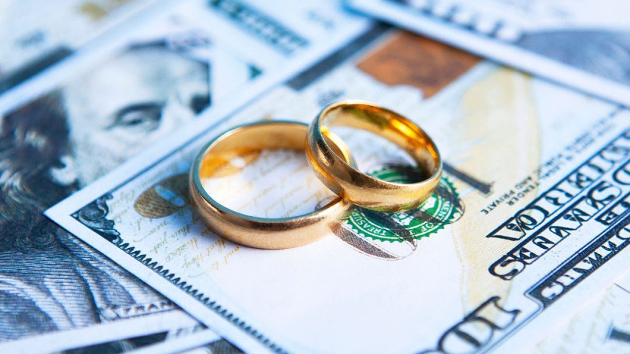 A pair of wedding rings on top of US banknotes.