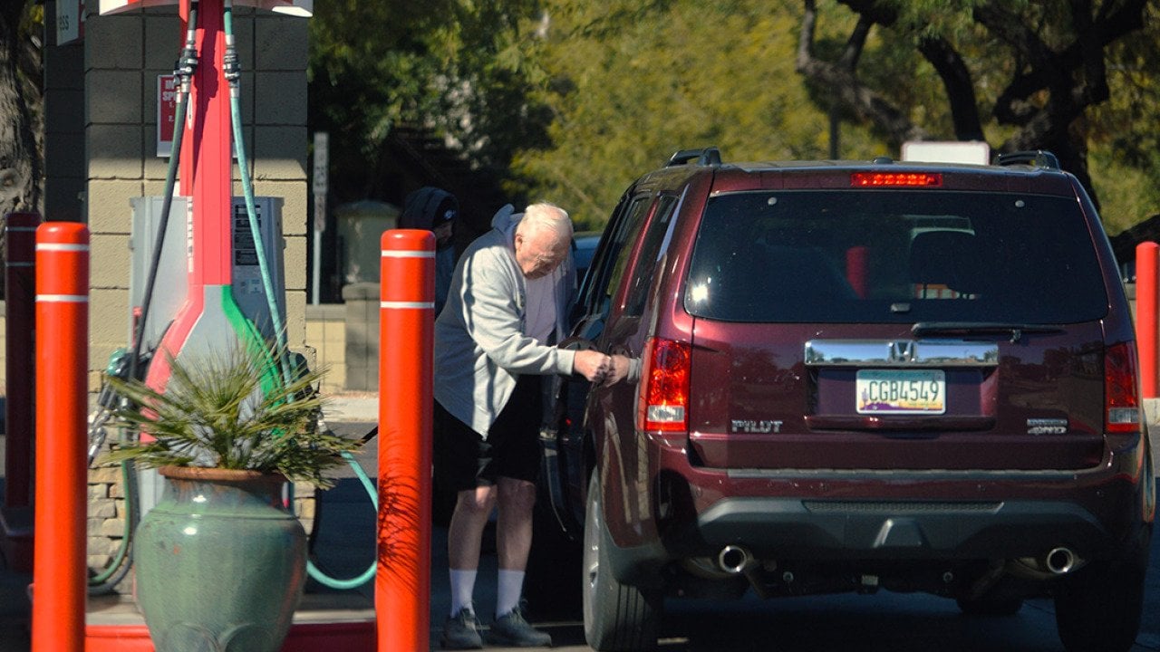 A senior citizen pumping gas into his car at a Safeway filling station in Chandler, Arizona, USA.