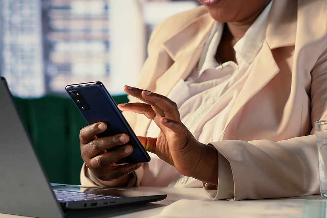 A businesswoman reading text messages from her phone while working in an office.