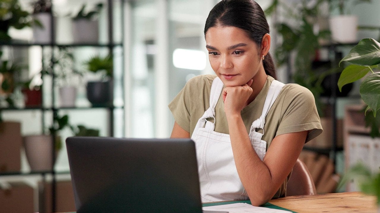A female small business owner using a laptop to review files.