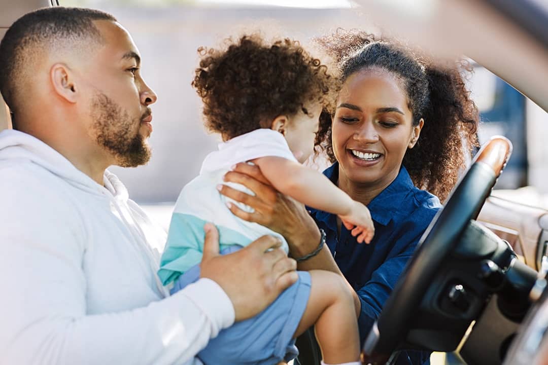 A mother taking her son out of the car during a stop in their road trip.