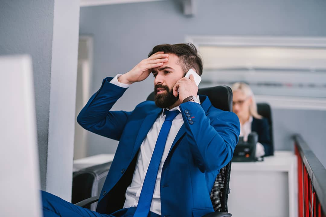 A business manager appearing to be frustrated during a phone call with a client. 