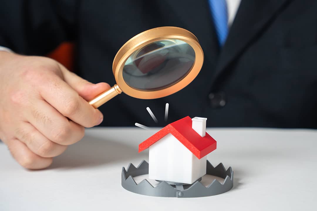 A lawyer examining a figure of a house enclosed in a trap as a concept of illegal property schemes.