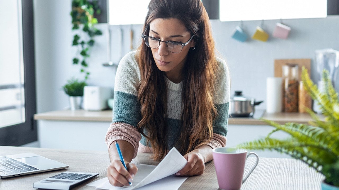A woman reviewing finance documents at home.