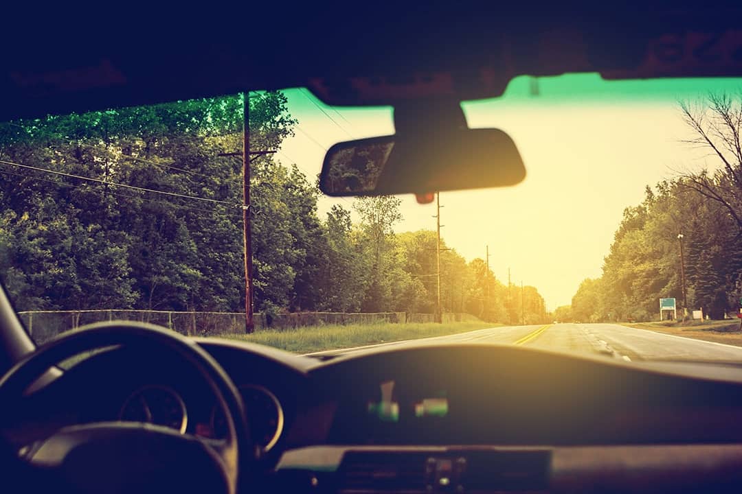 View from inside a car where sunlight is streaming through the windshield.