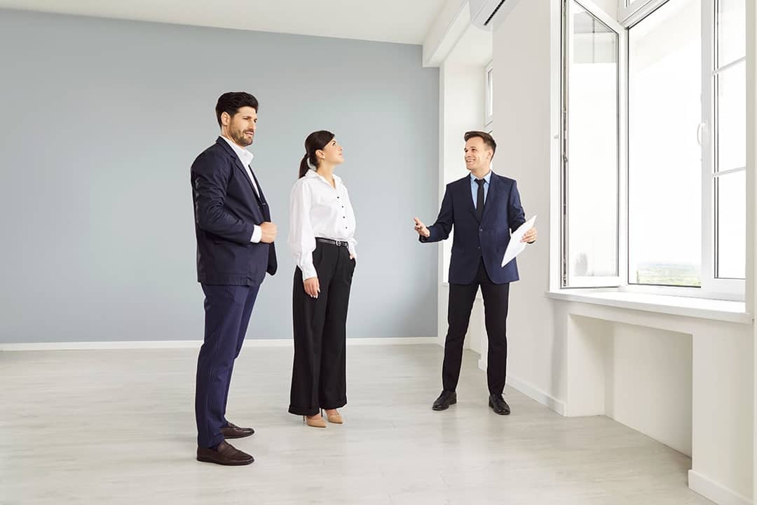A real estate agent showing an empty and new apartment to a married couple.
