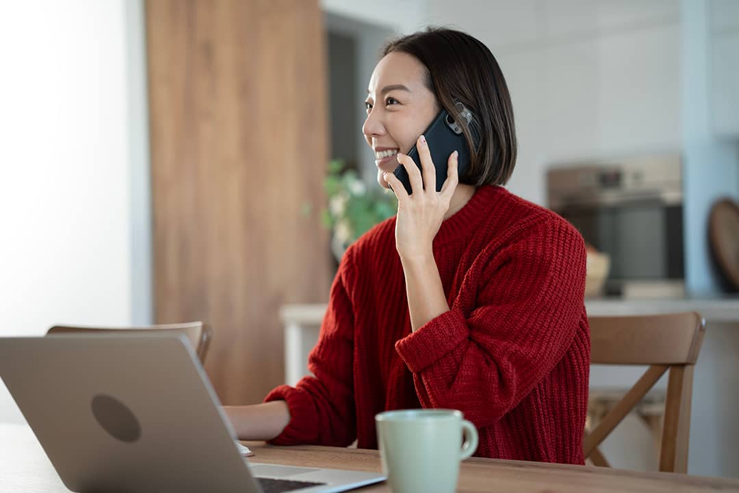 A young businesswoman on the phone while working from home.