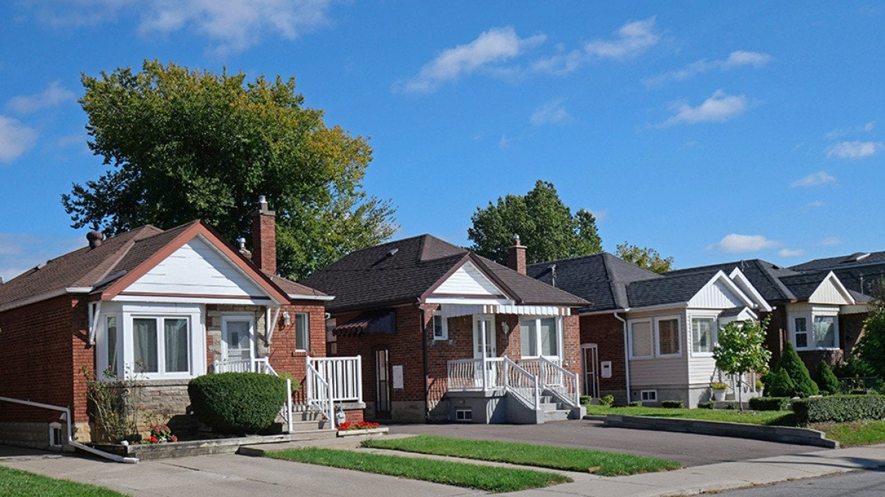 A row of detached bungalow-style brick homes in a street.