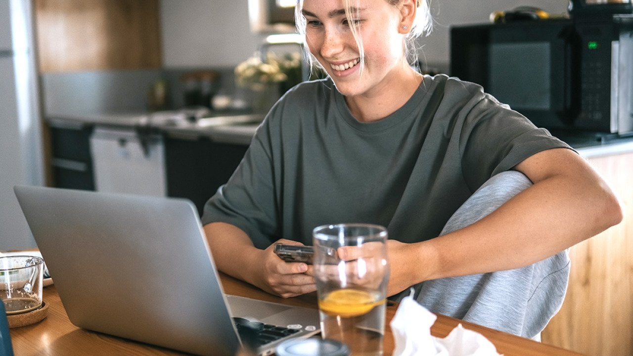 A young adult working remotely at her cozy kitchen at home.