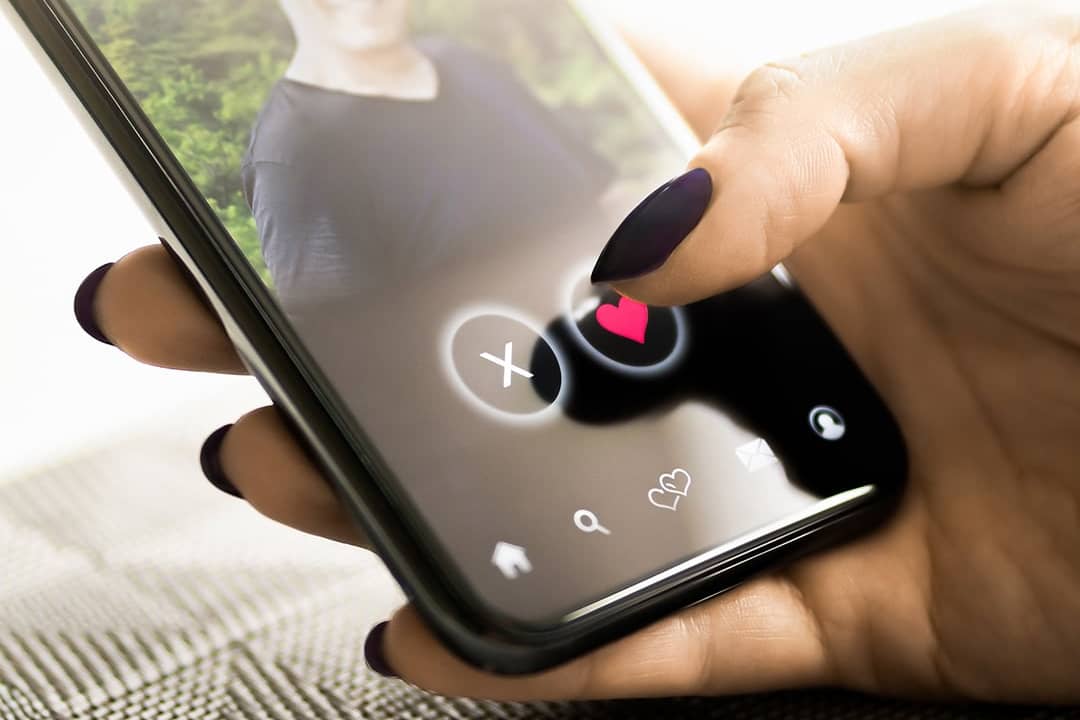 A person checking a profile of another person from a dating application in her smartphone.