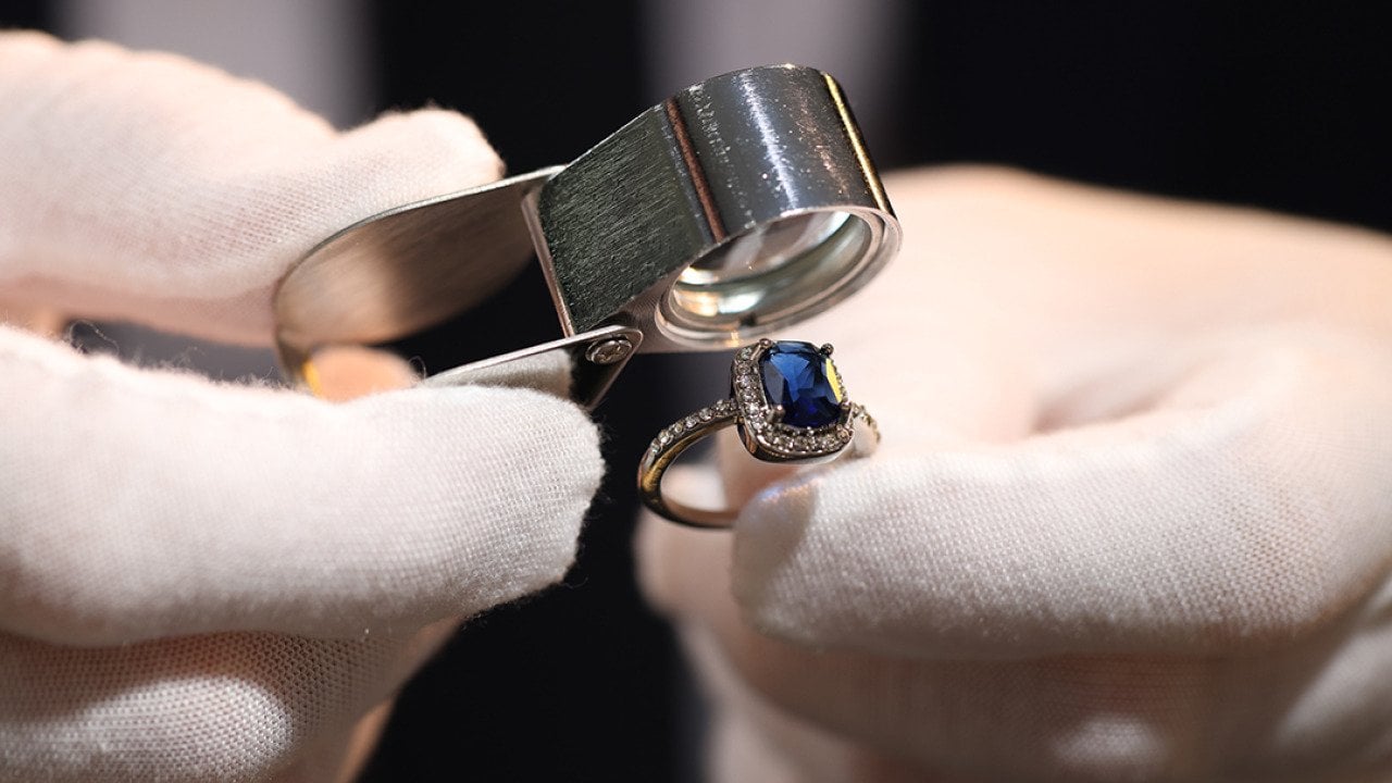 A jewelry appraiser using a loupe to evaluate a bejeweled ring.