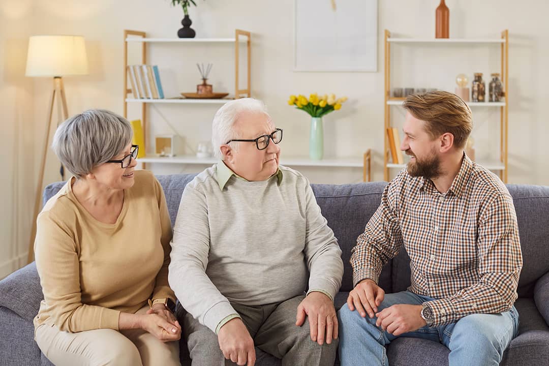 Senior parents and their adult son having a discussion at home.