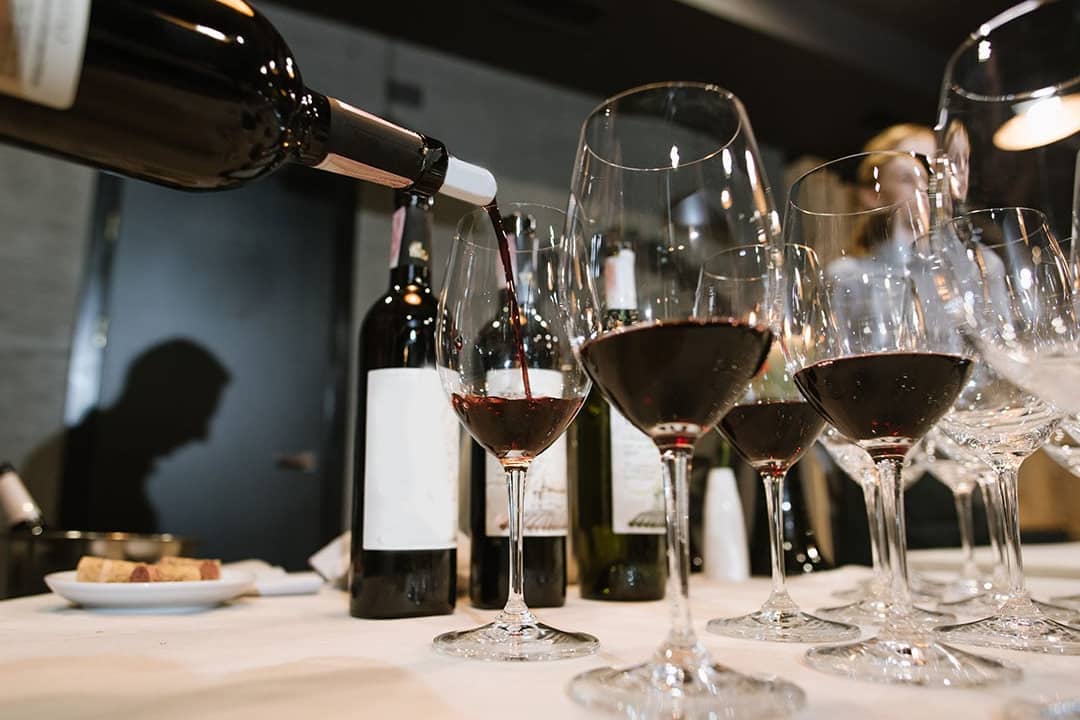 Wine being poured into glasses by a somelier at a restaurant.