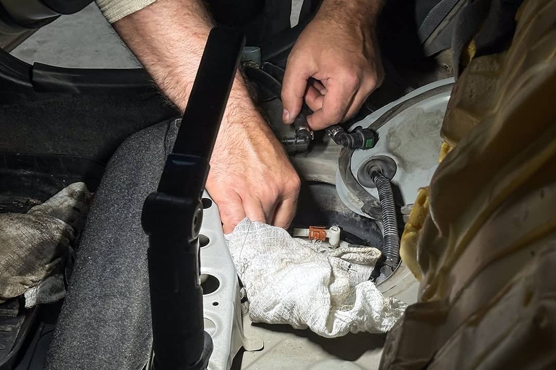 A mechanic checking car fuel pump pressure test during vehicle maintenance diagnostics.