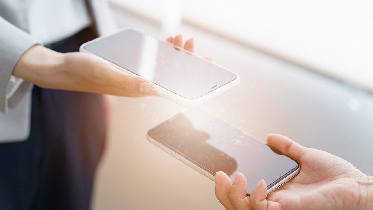 Two people's phones connecting via sync to exchange information.