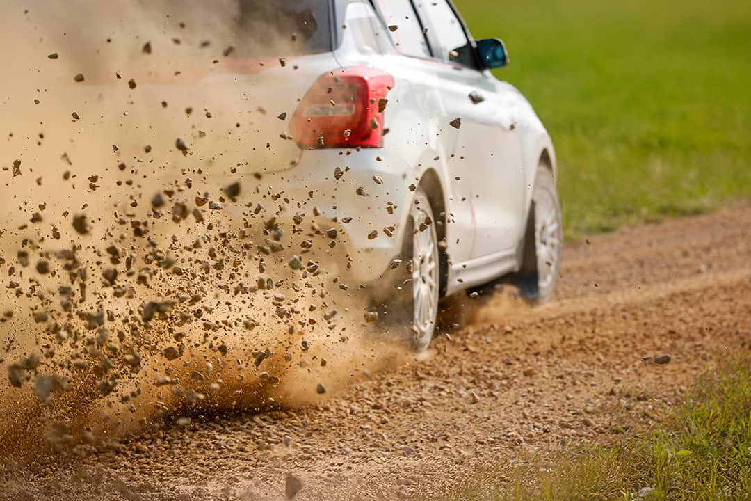 Gravel splashing from the wheels of a race car drifting on track.